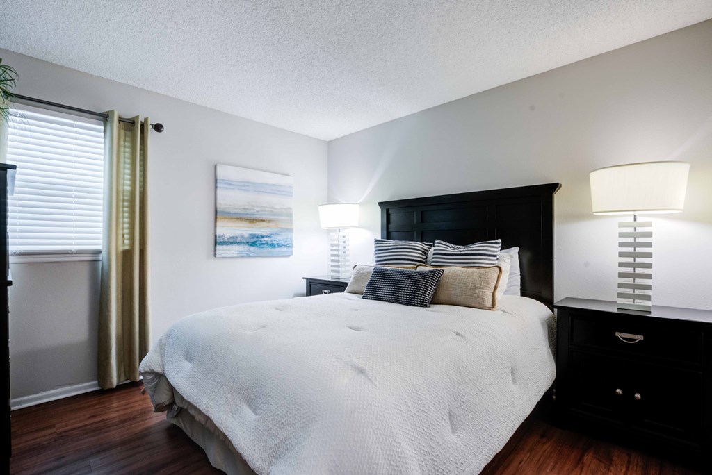 A bedroom with a large bed and a painting on the wall.