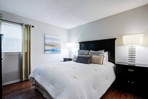 A bedroom with a large bed and a painting on the wall at Coral Club Apartments in Bradenton, FL