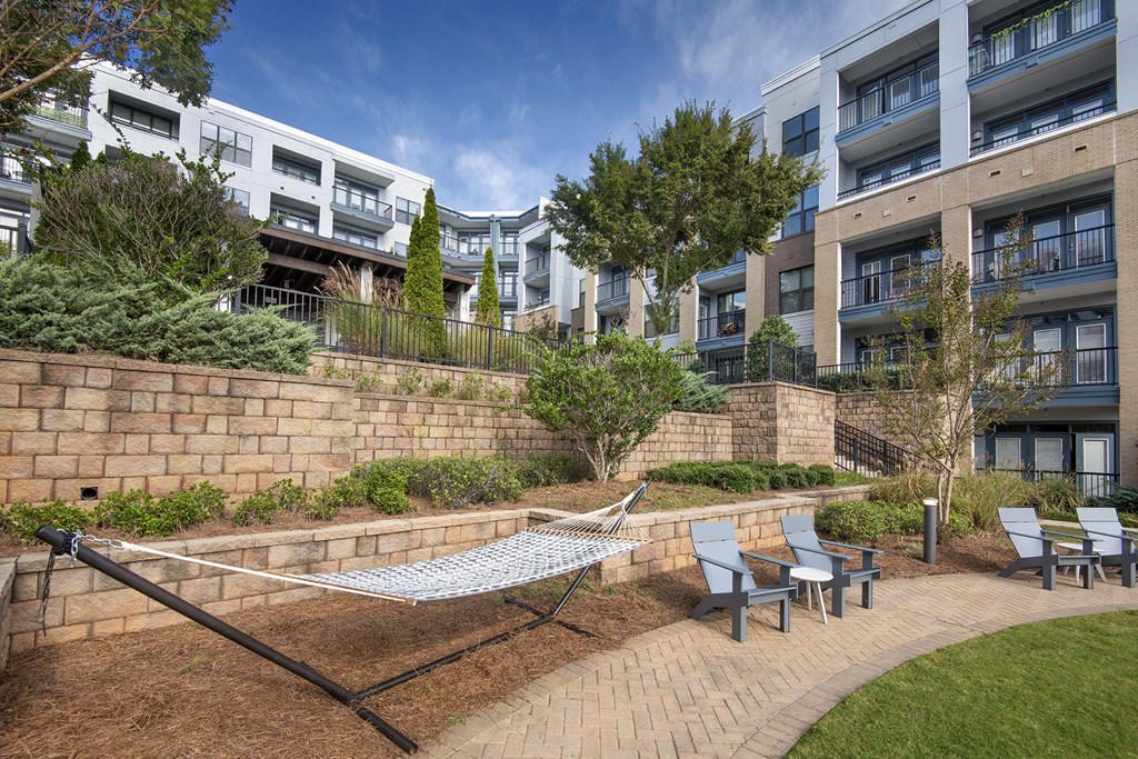 A hammock is strung between two poles in a courtyard with brick walls and trees.