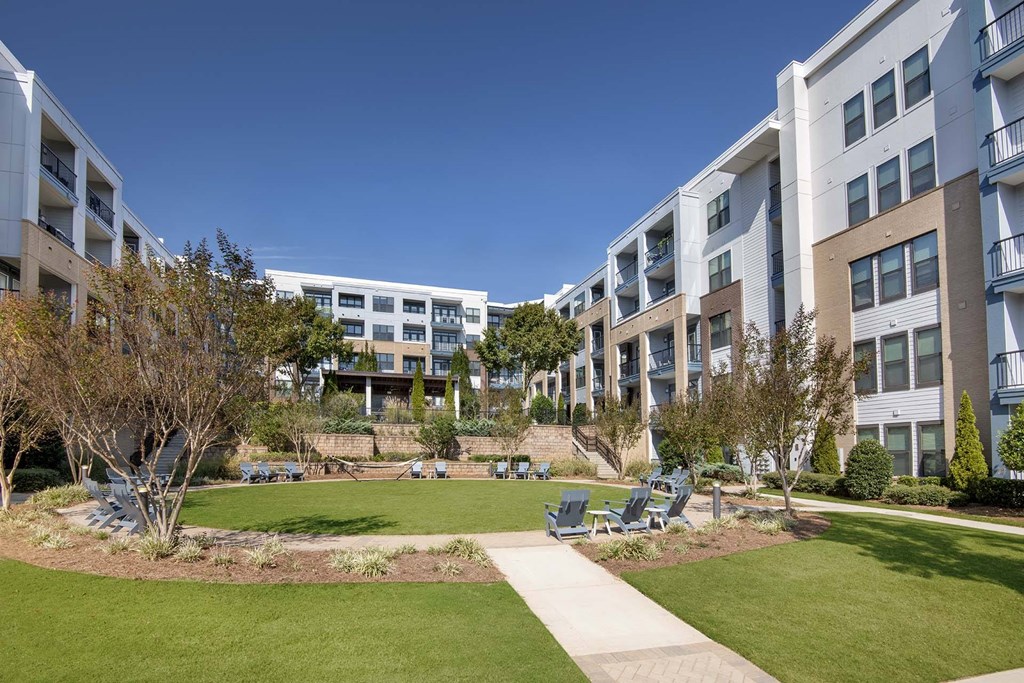 A sunny day at a residential complex with a well-maintained lawn and trees.