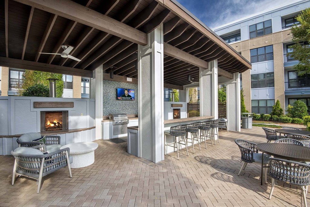A patio with a fireplace and chairs.