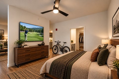 A bedroom with a large bed and a TV mounted on the wall.
