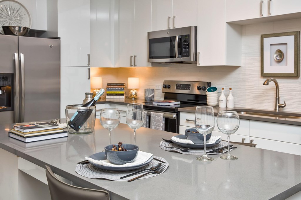 A modern kitchen with a dining table set for two.