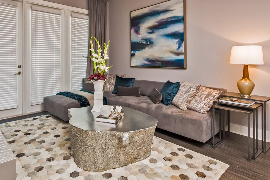 A living room with a grey couch, a coffee table, and a painting on the wall.