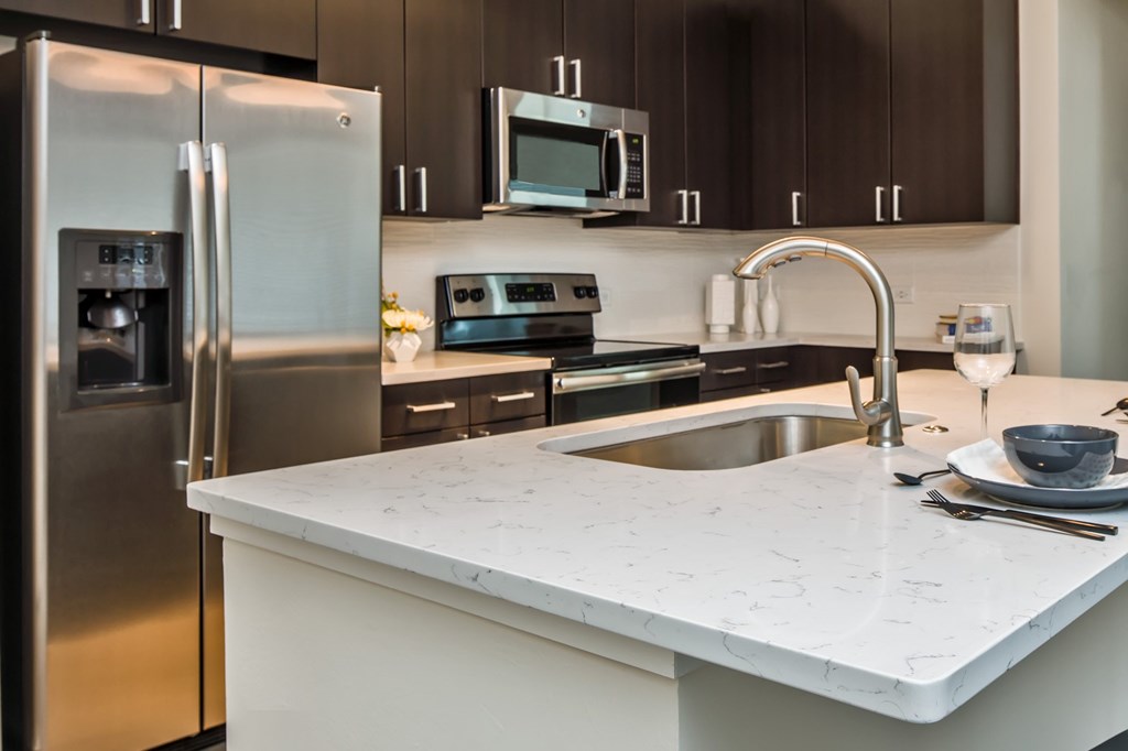 A modern kitchen with a stainless steel refrigerator and a marble countertop.