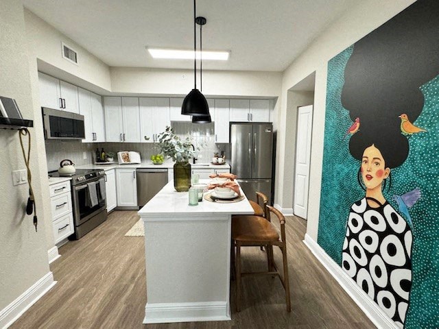 a kitchen with a table and a painting of a woman