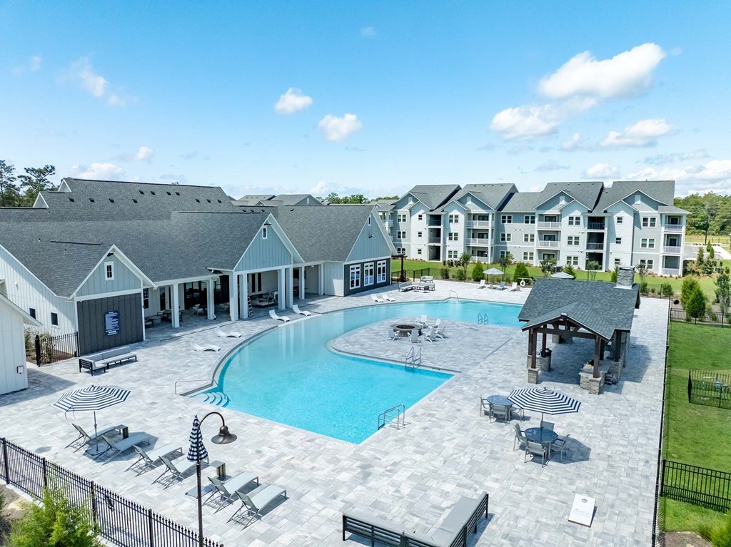 A large outdoor swimming pool with lounge chairs and a pavilion.