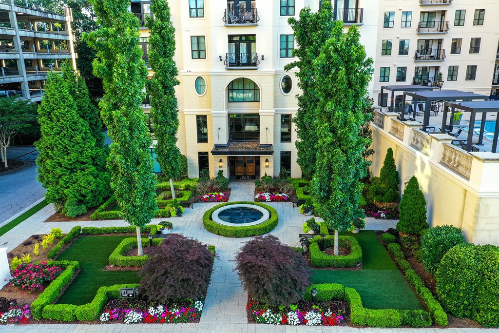 a courtyard with trees and flowers in front of a building