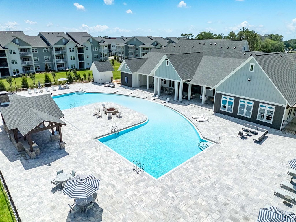 A large swimming pool surrounded by a patio and a building in the background.