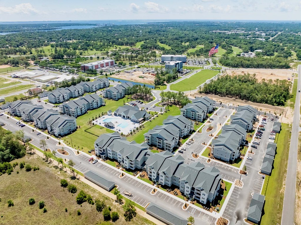 A large complex of grey buildings with a swimming pool in the middle.