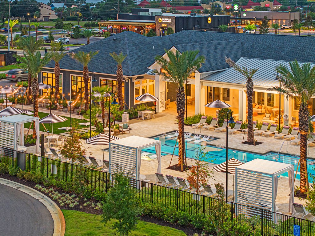 a resort style swimming pool with lounge chairs and umbrellas