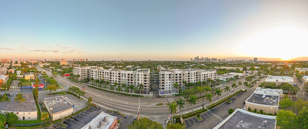 an aerial view of an empty parking lot with apartment buildings and a city skyline