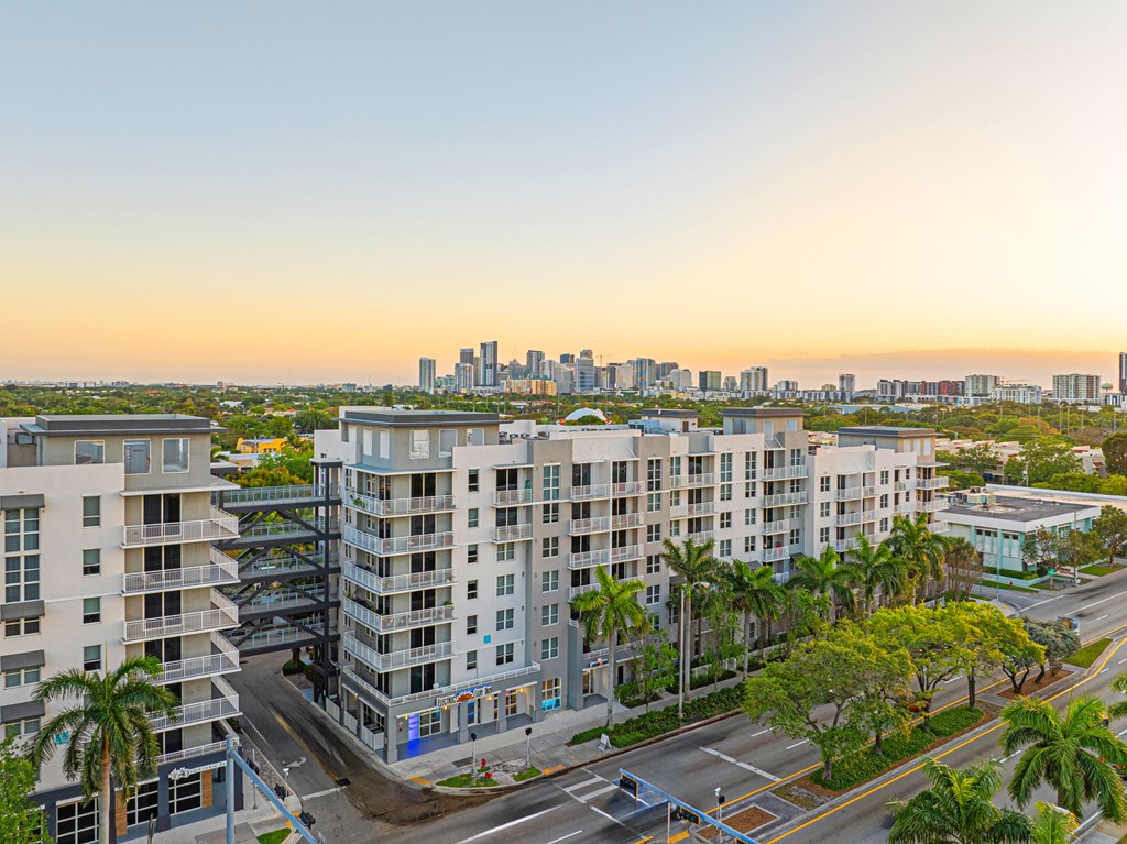 an aerial view of apartment buildings with palm trees and a city skyline in the background