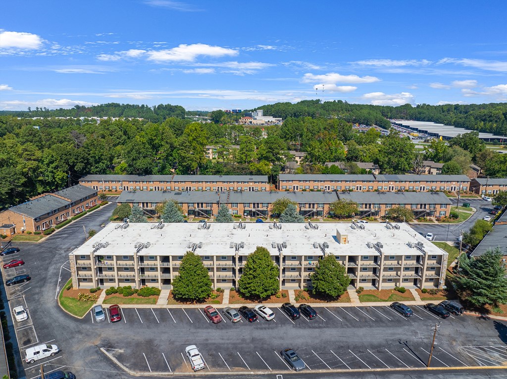 an aerial view of a large building with a parking lot and trees