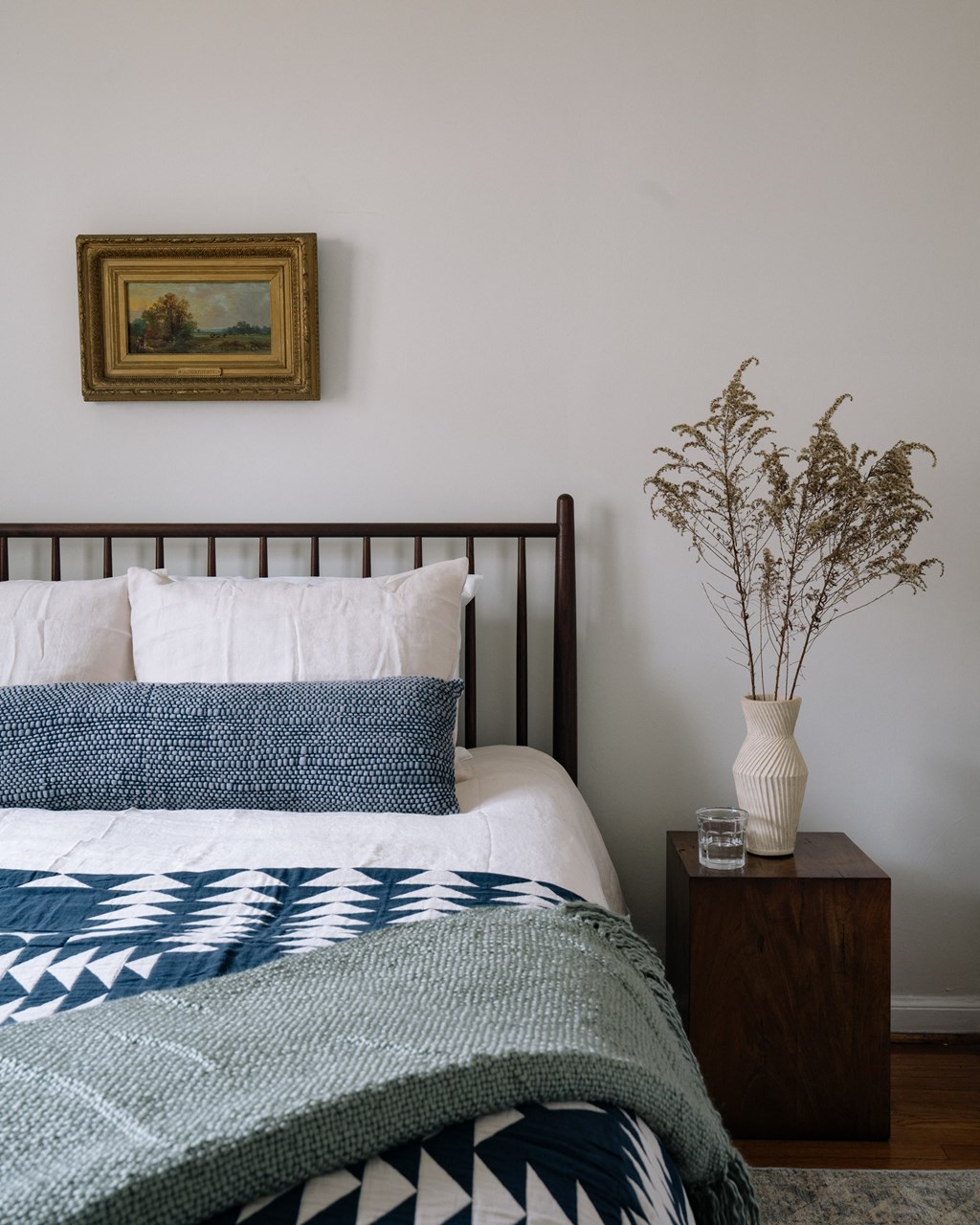 a bedroom with a bed and a vase with flowers