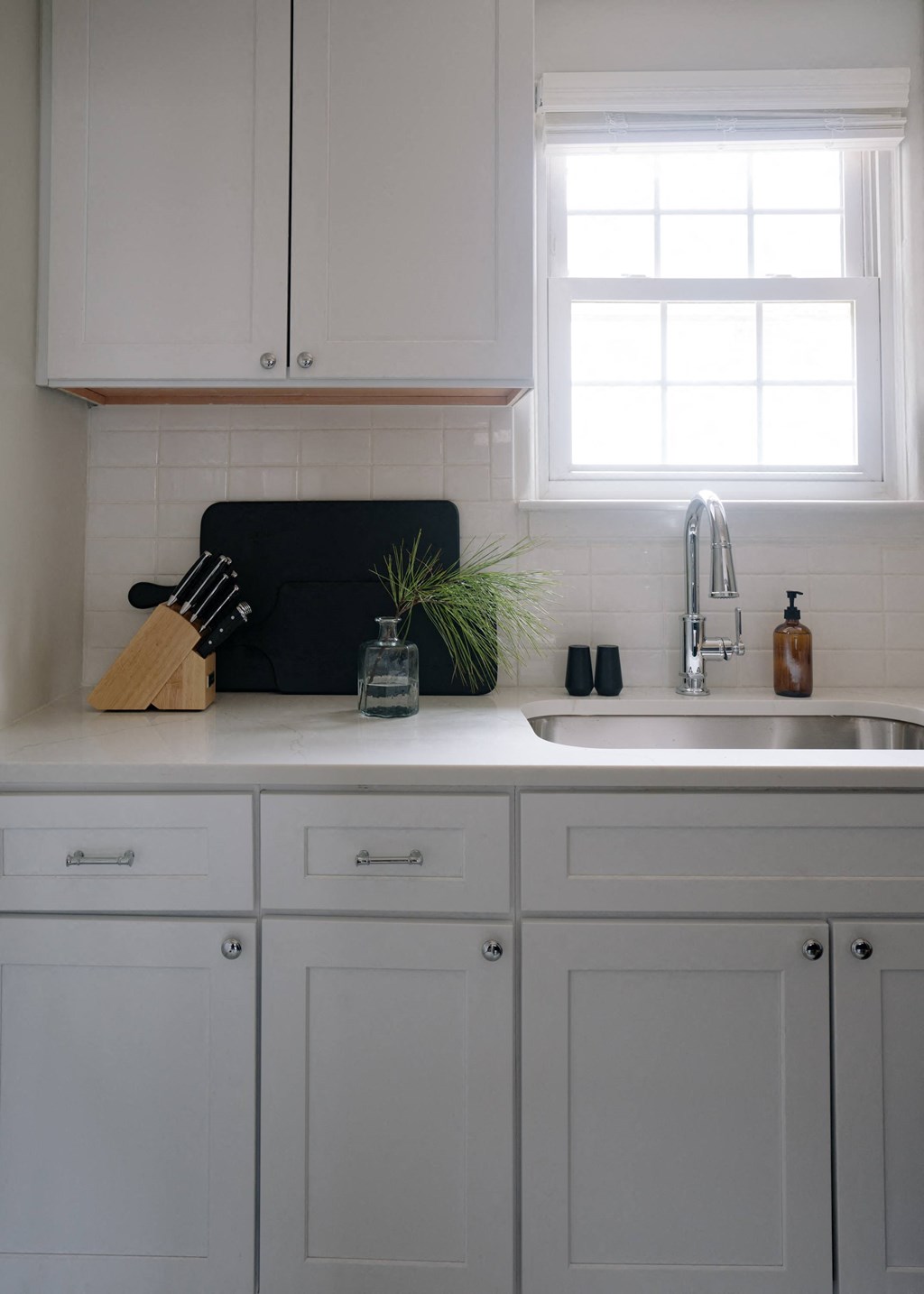 a white kitchen with white cabinets and a sink