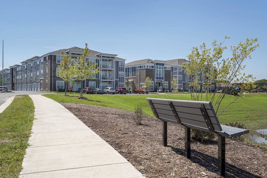 A bench is on the side of a concrete walkway.