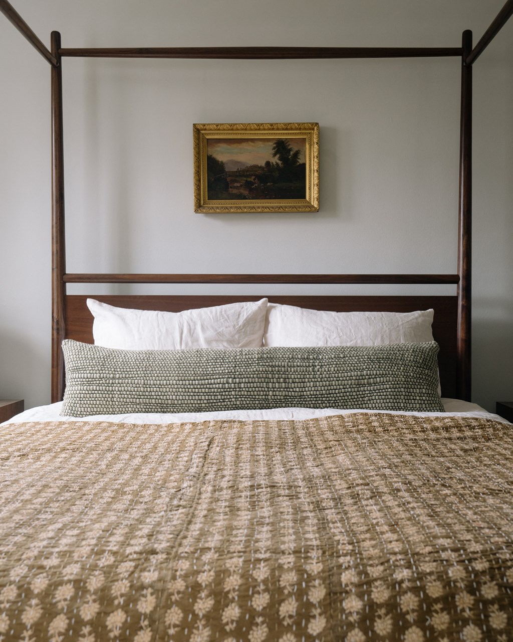 a bedroom with a bed and a painting on the wall