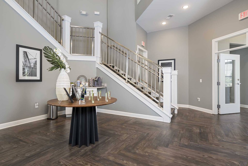 A foyer with a staircase and a table with a vase of flowers on it.