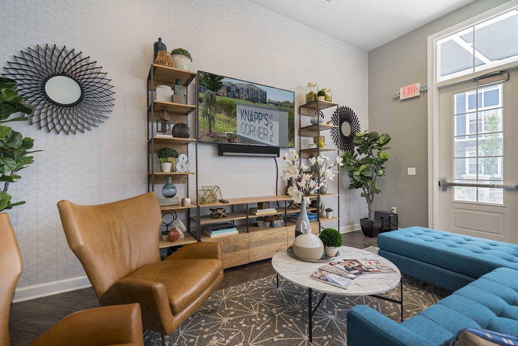 A living room with a brown leather chair, a blue sofa, and a coffee table with a vase of flowers on it.