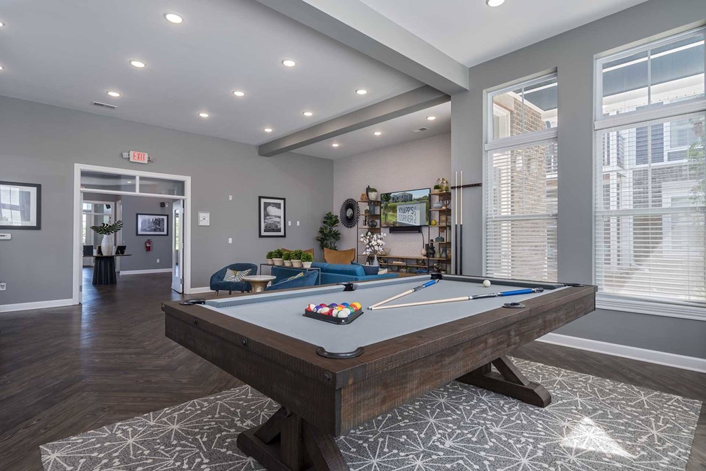 A pool table is in the middle of a room with a blue couch and a TV.