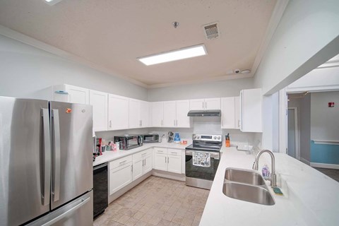 A kitchen with white cabinets and a stainless steel refrigerator.