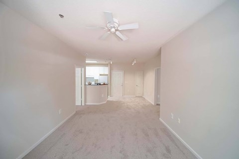 A spacious room with a ceiling fan and carpeted floor.