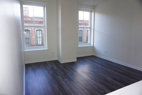an empty living room with wood floors and two windows