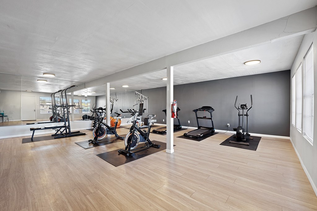A spacious gym with a variety of equipment including treadmills, stationary bikes, and weight machines.