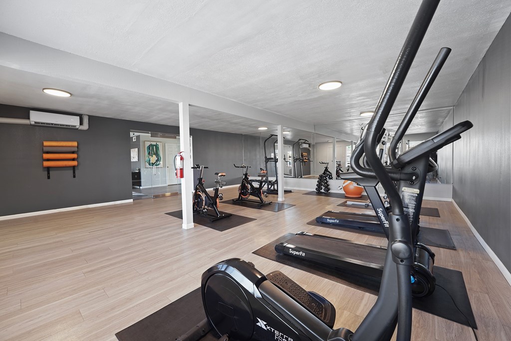 A gym with a variety of exercise equipment including treadmills, stationary bikes, and weights.