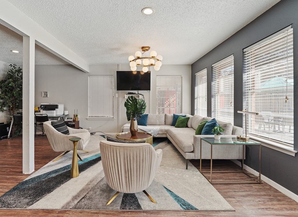 A living room with a white sofa, a coffee table, and a large window with blinds.