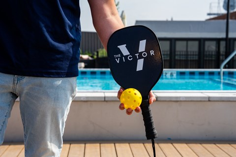 a man holding a paddle ball in his hand in front of a pool