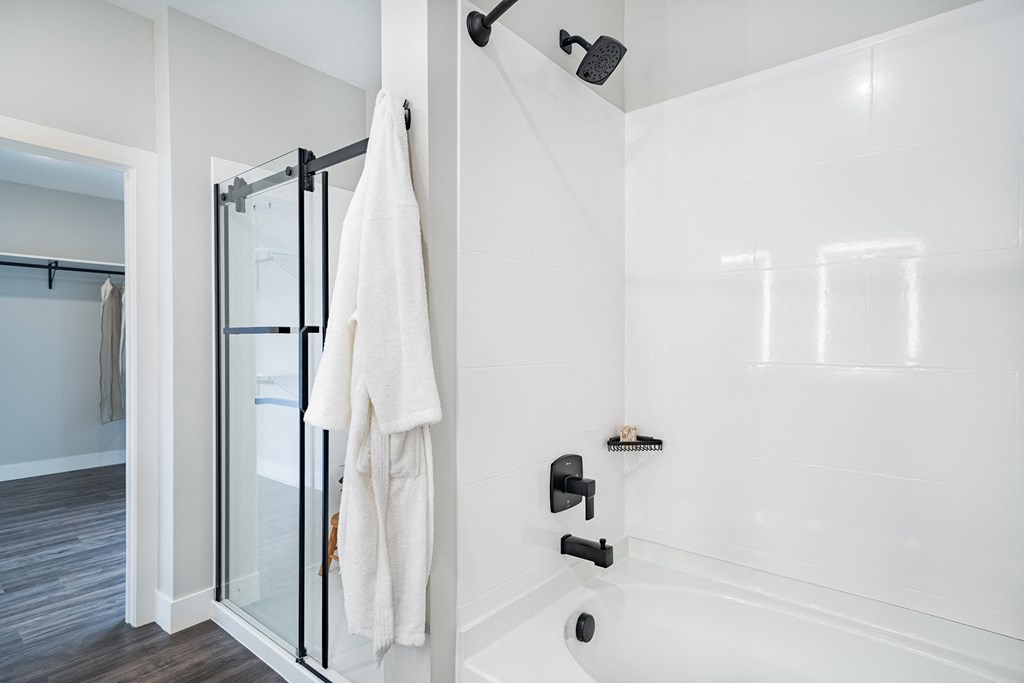 a white bathroom with a white tub and shower and a white towel