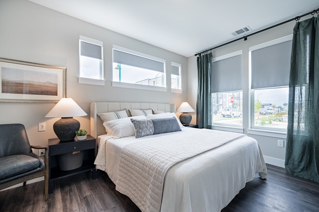 a bedroom with a large bed and large windows