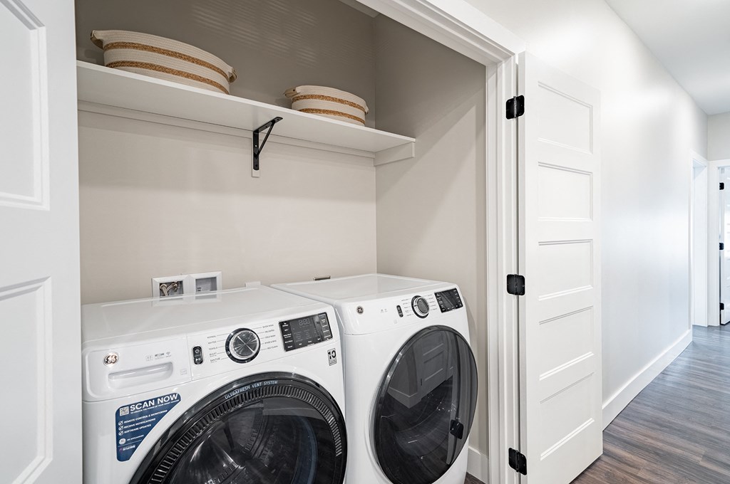 a white washer and dryer in a laundry room with a shelf above it