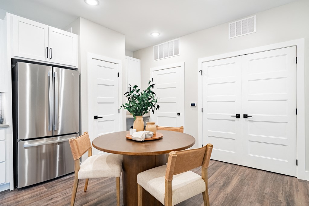 a dining room with a table and chairs and a stainless steel refrigerator