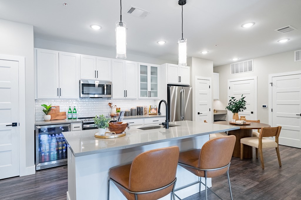 an open kitchen and dining area with white cabinets and a marble counter top