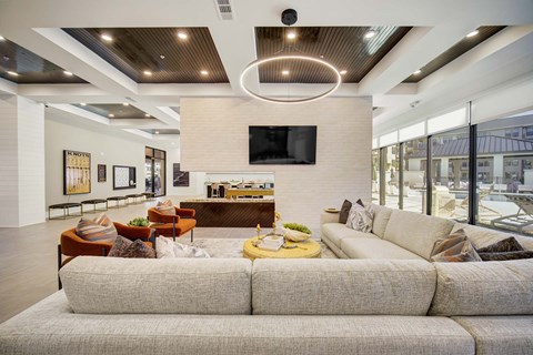 A modern living room with a large couch and a flat screen TV mounted on the wall.