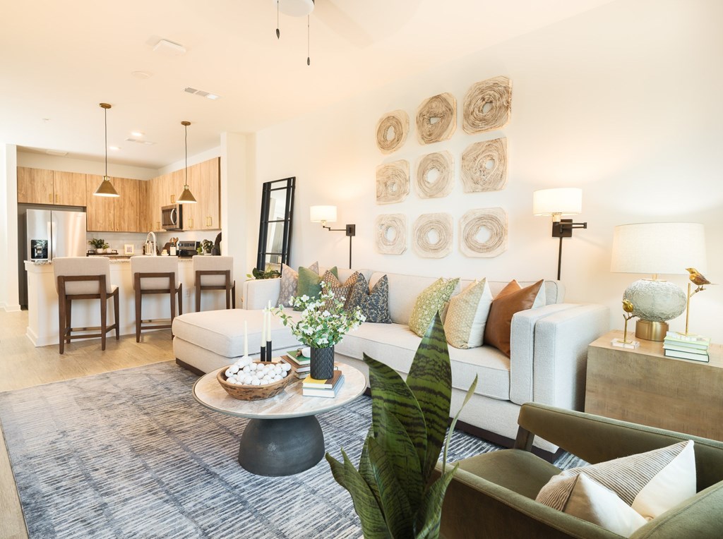 A modern living room with a white sofa, a coffee table, and a dining area in the background.