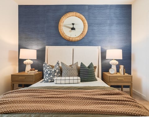 A bedroom with a bed, two nightstands, and a round mirror on the wall.