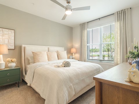 A well-lit bedroom with a large bed and a ceiling fan.