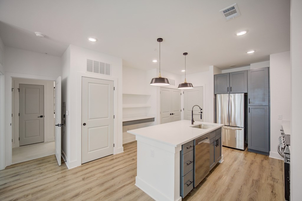 A modern kitchen with a white island and wooden floors.
