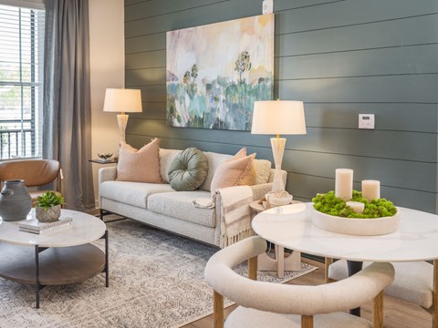 A living room with a white couch, a round table, and a painting on the wall.