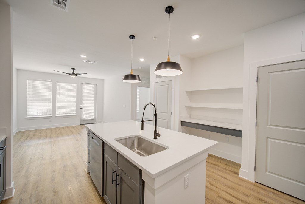 A modern kitchen with a white countertop and wooden flooring.