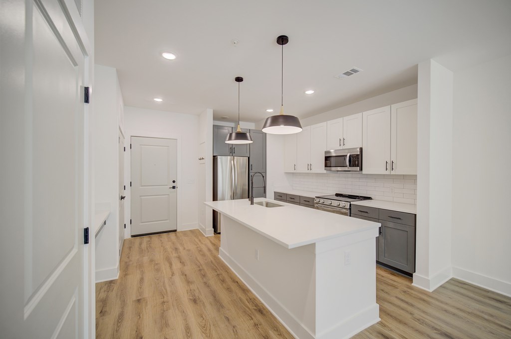 A kitchen with a white island and wooden floors.