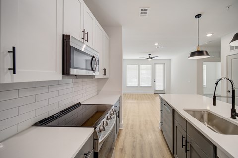 A modern kitchen with white cabinets and a wooden floor.