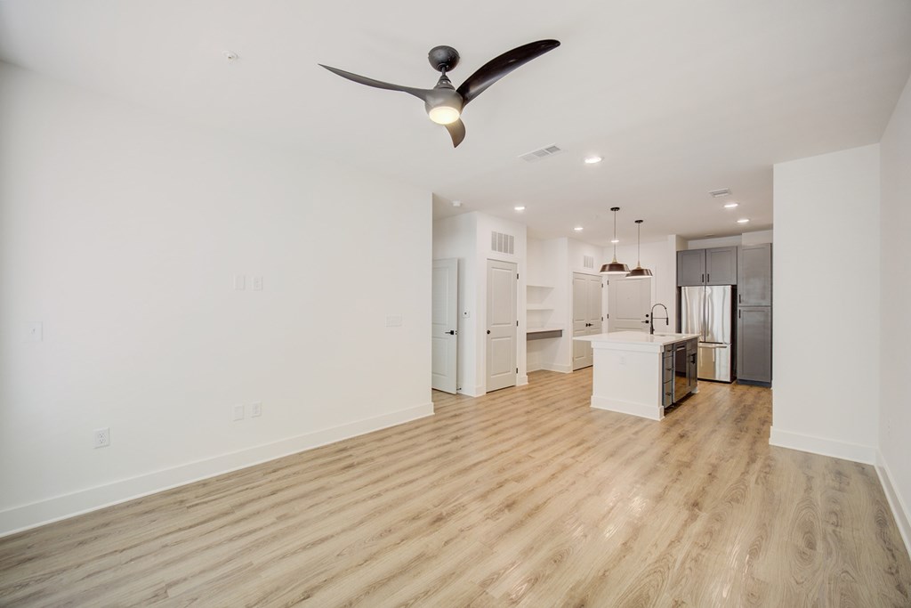 A room with a ceiling fan and wooden flooring.