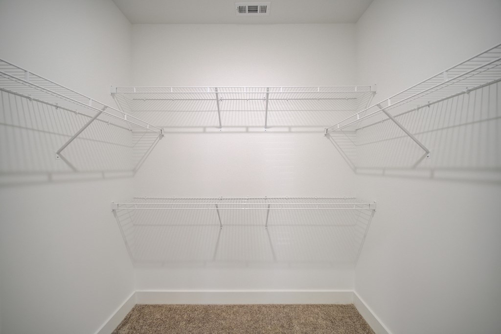Empty white walk in closet with shelves.