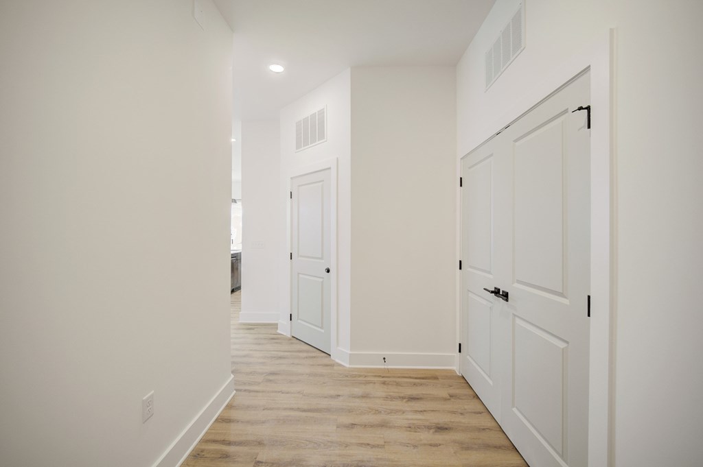 A long white hallway with a door on the right.