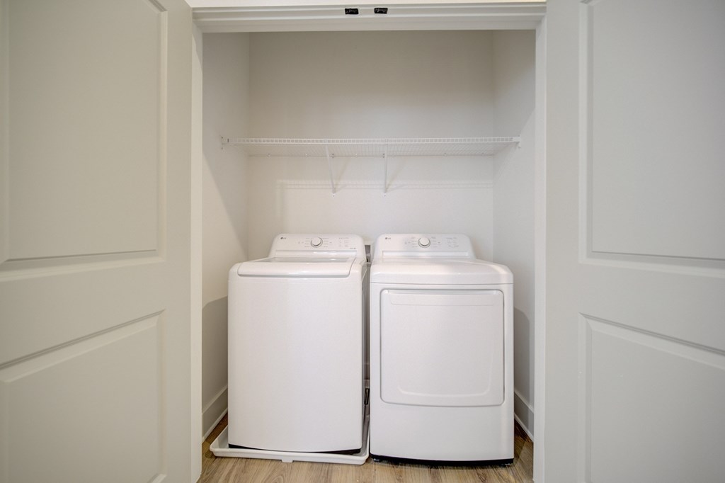Two white washing machines in a small laundry room.